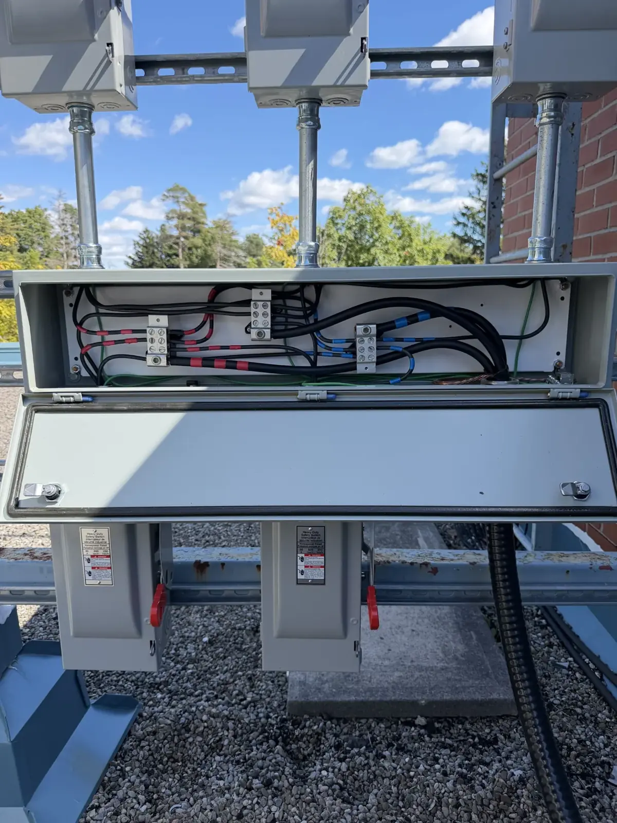Close view of an open rooftop wireway showing conductor routing to disconnect switches