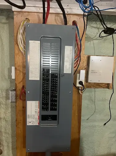Grey breaker panel with the cover on and a printed circuit directory, feeder cables entering from the top on a plywood backboard