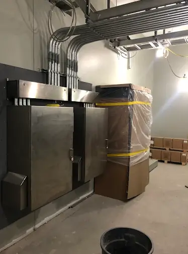 Stainless steel electrical enclosures with conduit entering from above in an unfinished commercial space
